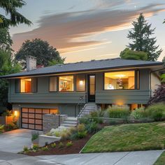 a large house with lots of windows in the front yard and landscaping around it at dusk