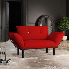 a red couch sitting on top of a rug in front of a mirror and potted plant