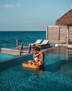 a man and woman sitting on a boat in the middle of an open pool with blue water