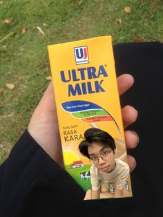 a person holding up a carton of ultra milk