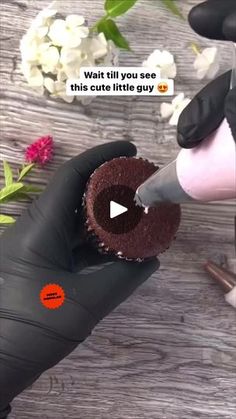 a person cutting into a chocolate cake with a knife on the table next to flowers