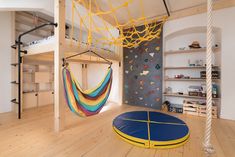 a room with a hammock, bookshelf and climbing wall