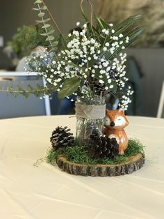 a vase filled with white flowers sitting on top of a wooden stump next to a pine cone