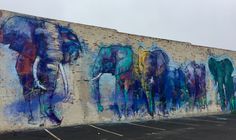 an elephant mural painted on the side of a building in front of a parking lot