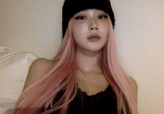 a woman with long pink hair wearing a black beanie and looking at the camera