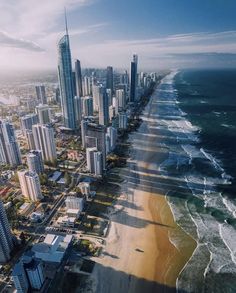 an aerial view of surfers on the beach and high rise buildings in the background