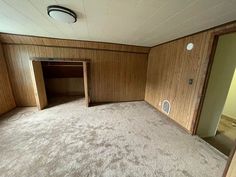 an empty room with wood paneling and carpet