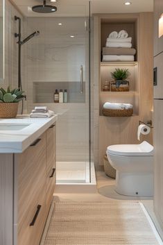 a bathroom with a toilet, sink and shower stall is shown in this image there are towels on the shelves above the toilet