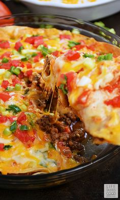 a close up of a pizza on a pan with one slice being lifted from it