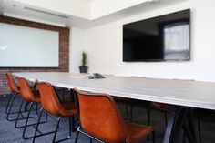 a long table with chairs and a flat screen tv on the wall in an office