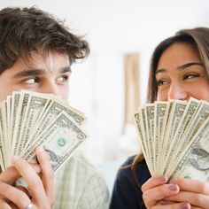 a man and woman are looking at each other with money in front of their faces