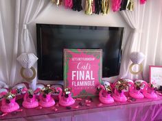 pink flamingos are sitting on the table in front of a flat screen tv and decorations