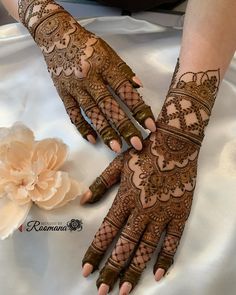 two hands with henna tattoos on them and a flower in the foregrounds