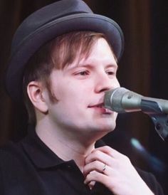 a young man wearing a hat and holding a microphone in front of his face as he sings