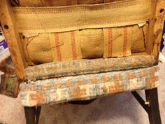 an old wooden chair with some fabric on it's back and seat cushion removed