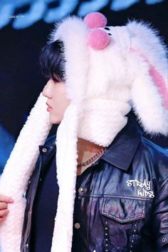 a man wearing a white bunny hat and black leather jacket with pink pom - poms