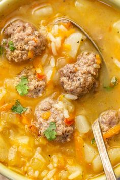 a bowl filled with soup and meatballs on top of it next to a spoon