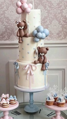 a three tiered cake with teddy bears on top and cupcakes in the bottom