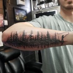 a man with a fishing pole and trees tattoo on his arm