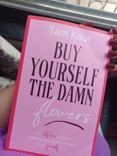 a person holding up a pink sign that says buy yourself the damn flowers on it