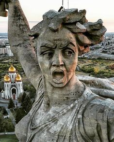 a statue with a bird perched on it's head in front of a cityscape