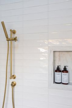 a shower head with two bottles of soap in it and a gold faucet