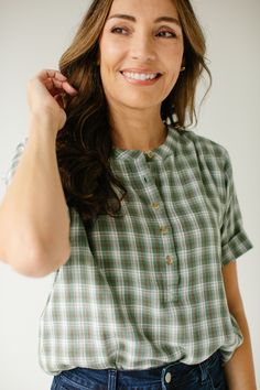 The 'Fern' top makes us reminisce about apple orchards, campfires, and fall leaves! The top features a modest neckline with functioning buttons, cuffed sleeves, and comes is a sweet soft green plaid. Dress it up with denim and wedge sandals for a night out, or a cardigan and boots for everyday wear! 100% Cotton Machine Wash Cold with Like Colors Hang or Lay Flat to Dry Do Not Bleach Warm Iron If Needed Model Height 5'9" | Wearing Size XS Wearing the 'Fern' Cotton Plaid Top with the 'Krista' Deni Green Camp Collar Top With Button Closure, Washed Cotton Plaid Tops, Green Soft-washed Cotton Tops, Plaid Button-up Top With Pockets, Green Cotton Button-up Flannel Shirt, Modest Neckline, Layered Tops, Green Plaid, Plaid Tops