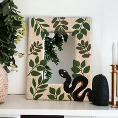 there is a decorative frame with a snake on it next to a potted plant