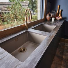 a kitchen sink sitting under a window next to a counter top with a faucet