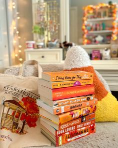 a stack of books sitting on top of a bed next to a pillow and pillows