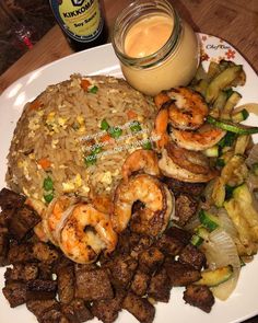 a plate with shrimp, rice and vegetables on it next to a bottle of mustard