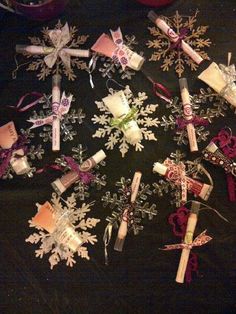 snowflakes and candles are arranged in a circle on a black tablecloth with ribbons