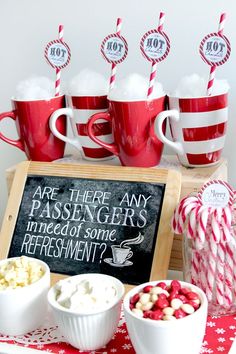 red and white candy canes are in cups with marshmallows on the table