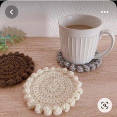 two crocheted coasters sitting next to a cup of coffee