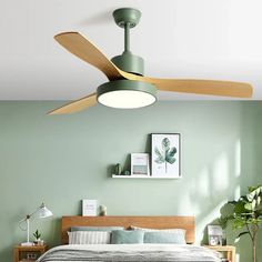 a bedroom with a bed, ceiling fan and pictures on the wall above it in shades of green