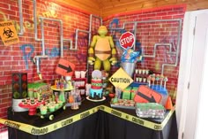 a table topped with cakes and candy covered in yellow caution tape next to a red brick wall