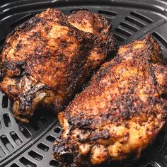 two pieces of cooked chicken sitting on top of a grill grates in an air fryer