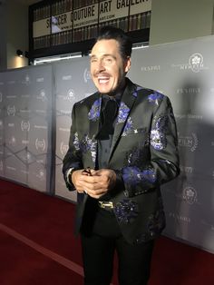 a man in a suit standing on a red carpet