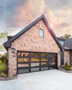 a large brick house with two garage doors on the front and one door open to let in light