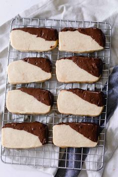 four cookies on a cooling rack with chocolate frosting and white icing in the middle