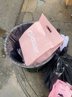 a pink bag sitting on top of a trash can next to other bags and garbage