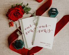 two wedding rings are laying on top of a red ribbon next to a card that says out our new years