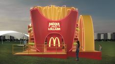 a man standing in front of a giant mcdonald's sign on top of a field