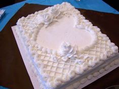 a square cake with white frosting and flowers on the top is sitting on a table