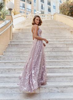 a woman in a pink dress standing on some steps