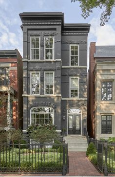 two story brownstone home with wrought iron fence and gated yard in the foreground