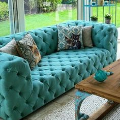 a living room filled with blue couches next to a wooden table and large windows