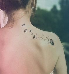 the back of a woman's neck with a dandelion tattoo