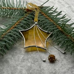 an ornament hanging from a christmas tree branch with a pine cone on it