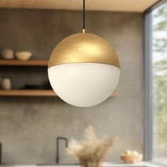 a white and gold light hanging over a kitchen counter top next to a bowl of wheat